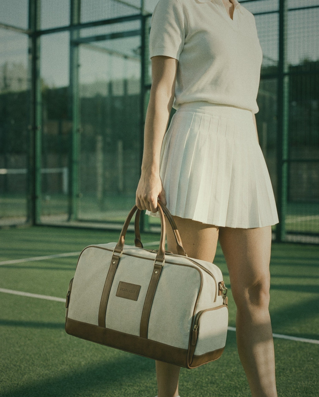 The Match Kit held by its cognac handles on a padel court