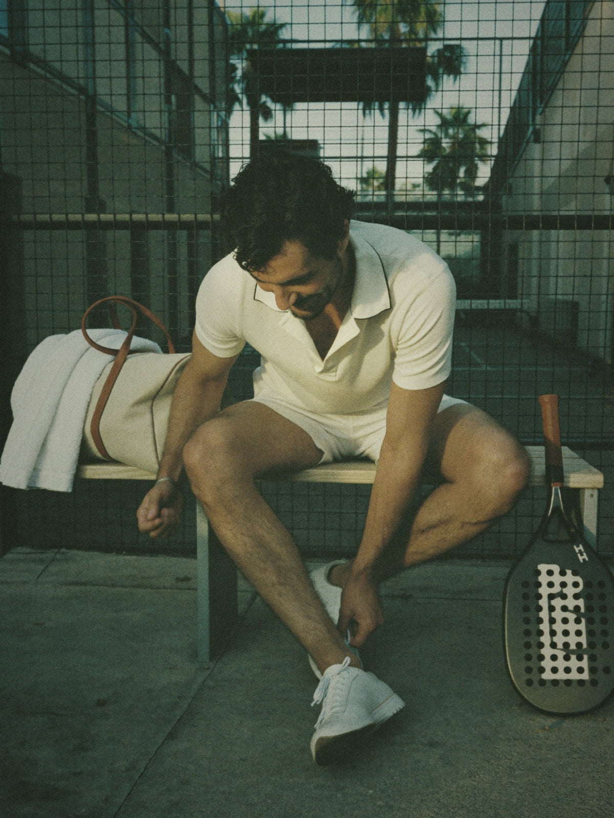 A player ties his shoes on a courtside bench next to The Match Kit bag
